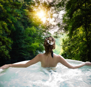 Private mineral hot tub at Sycamore Mineral Springs, surrounded by lush greenery.